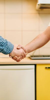 Repairman in uniform and customer shake hands, handyman. Professional worker makes repairs around the house, home repairing service